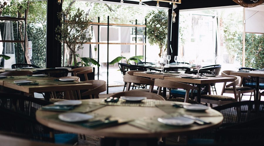 Salón interior de Princi.Pico con mesas de madera y plantas